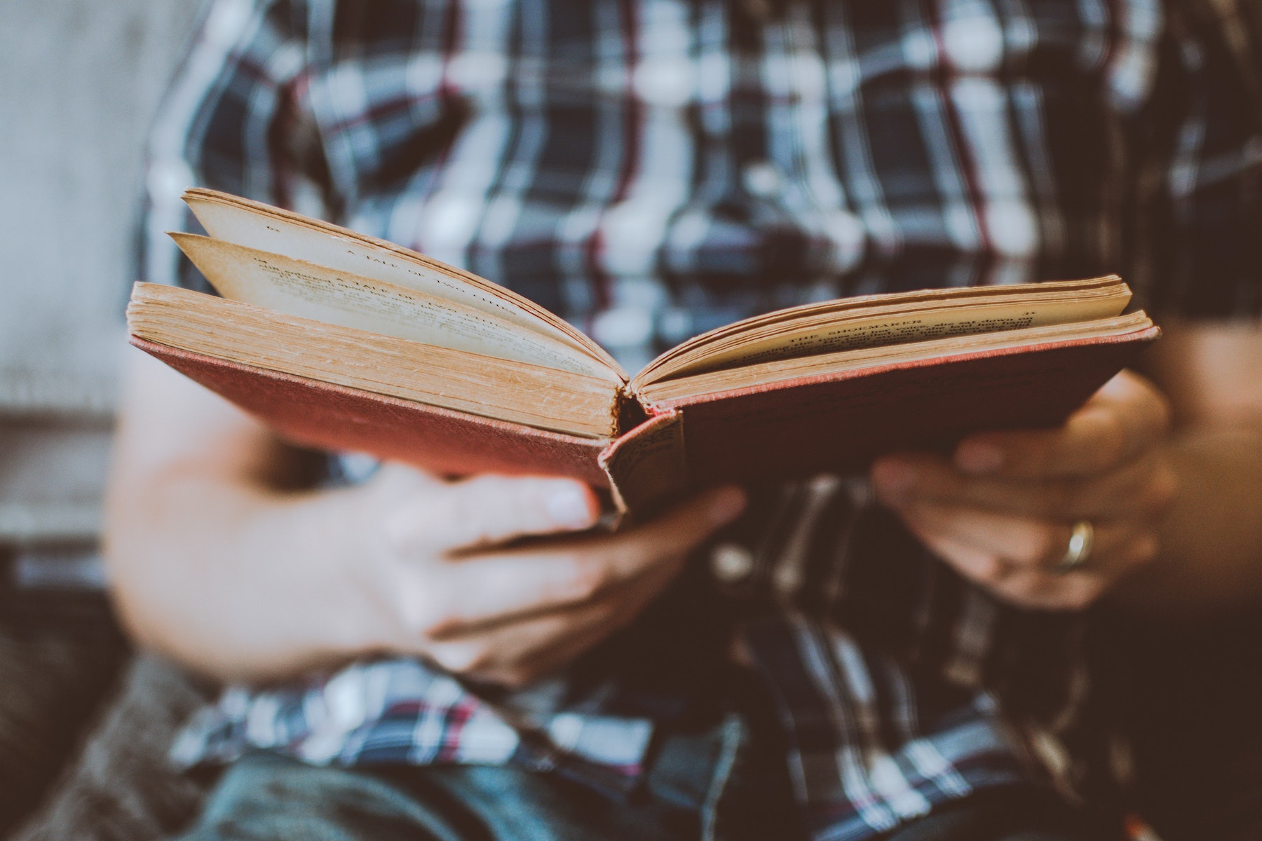 persona con camicia a quadri che legge poesie su un libro